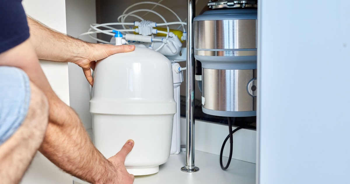 Gros plan sur un réservoir d'osmoseur domestique installé sous un évier.