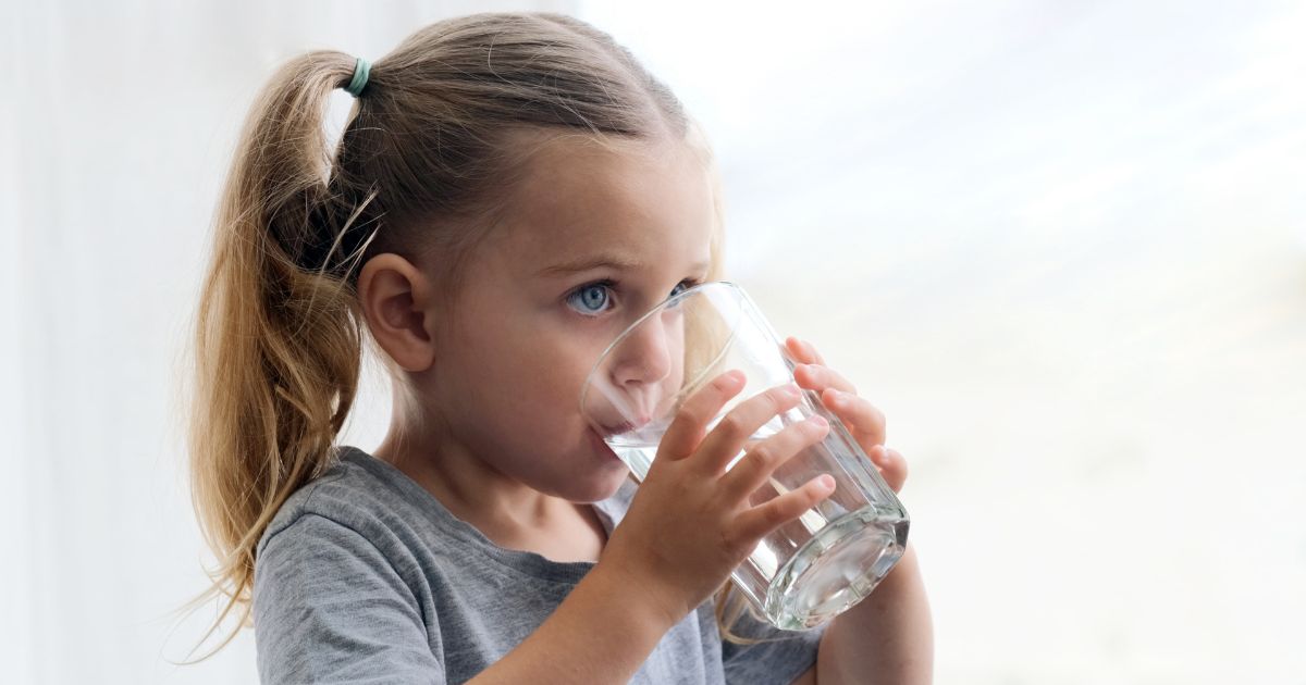 Petite fille buvant de l'eau adoucie dans un verre.