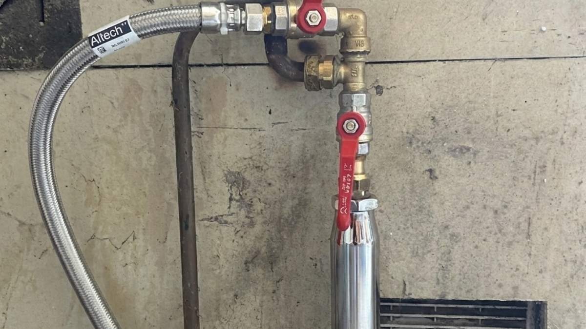 Adouciseur en zinc aquasain fixé sur une tuyauterie dans une buanderie.